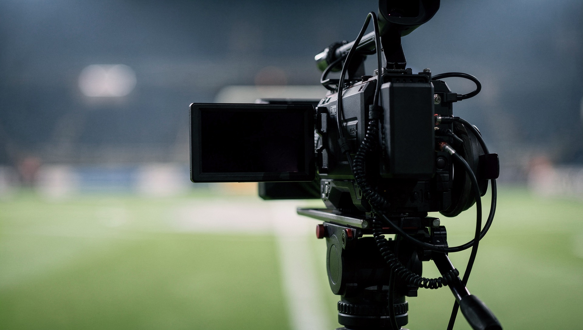 AI illustration of a plain broadcast camera with a dark monitor and blurred sporting background.